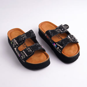 Pair of black sandals with brown soles on a white background
