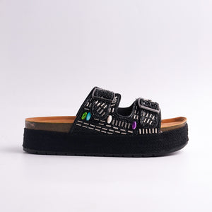 Black sandal with decorative elements on a white background