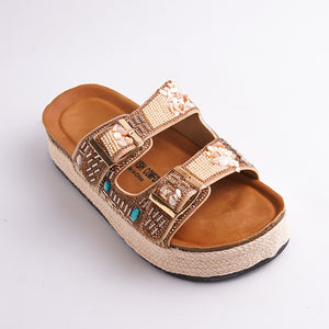 Decorative sandal with gold embellishments and turquoise stones on a white background