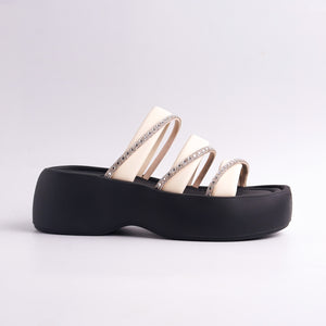 Black and beige sandals with decorative straps on a light gray background