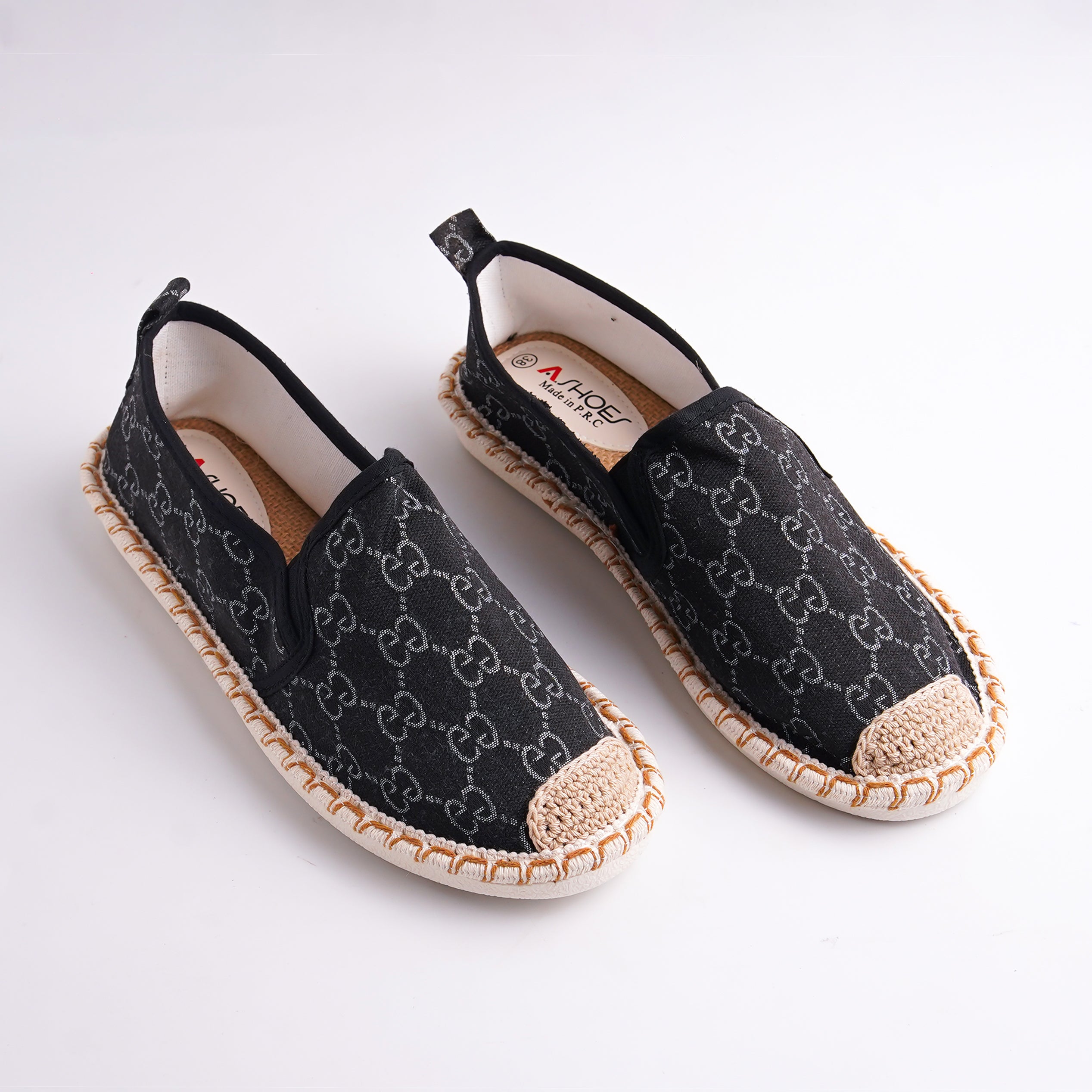 Black espadrille shoes with a pattern on a white background