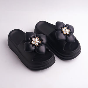 Pair of Black Platform Flower Slides with rhinestone jewel center on a white background.