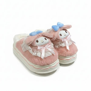 Pair of pink slippers with cartoon face design on a white background