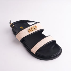 Black sandal with beige strap and gold logo on a light gray background