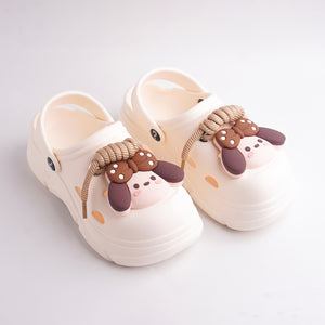 Pair of beige clogs with cartoonish animal decorations on a light gray background