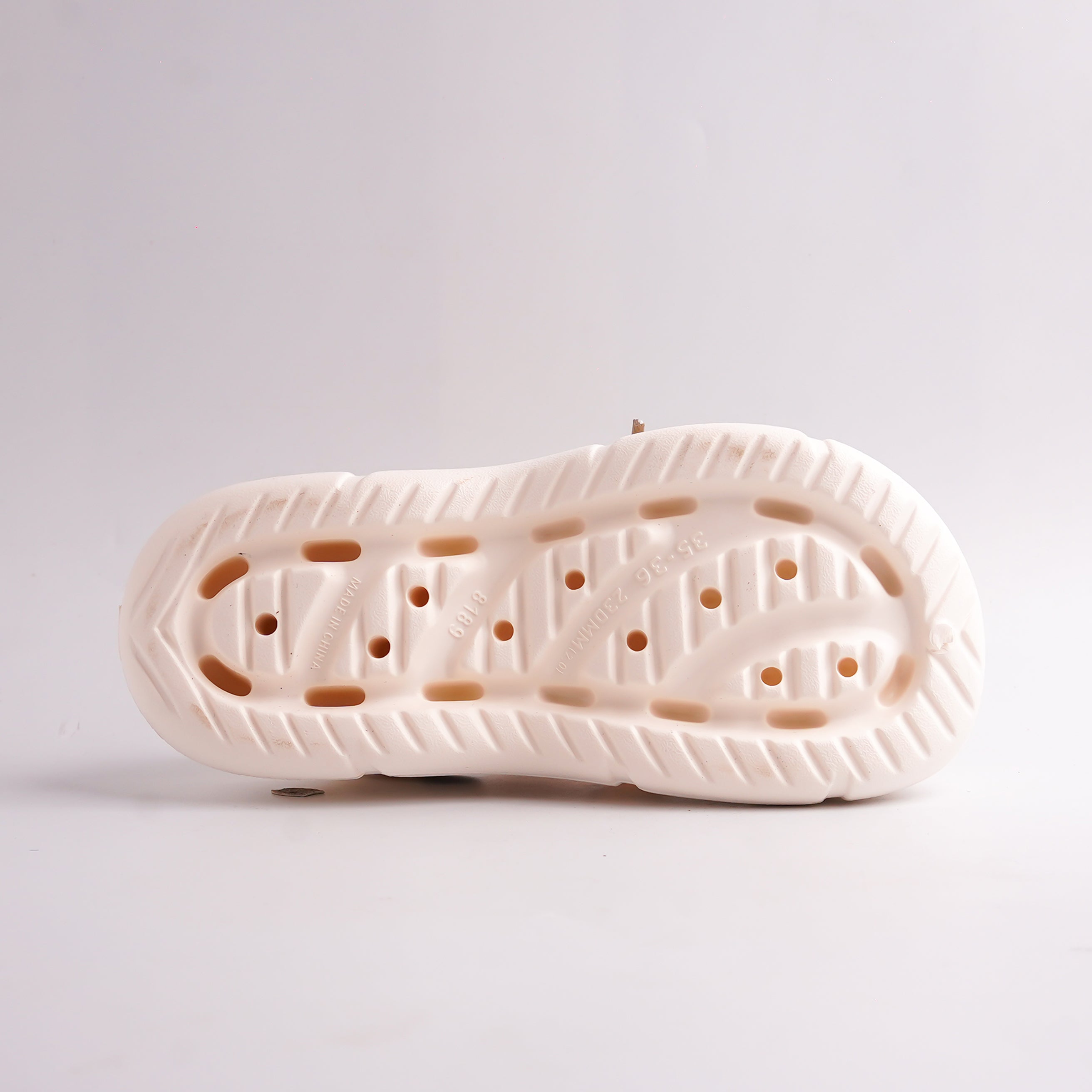 Close-up of a white shoe sole with a textured pattern on a light gray background