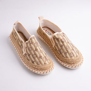 Pair of beige espadrille shoes with a pattern on a white background