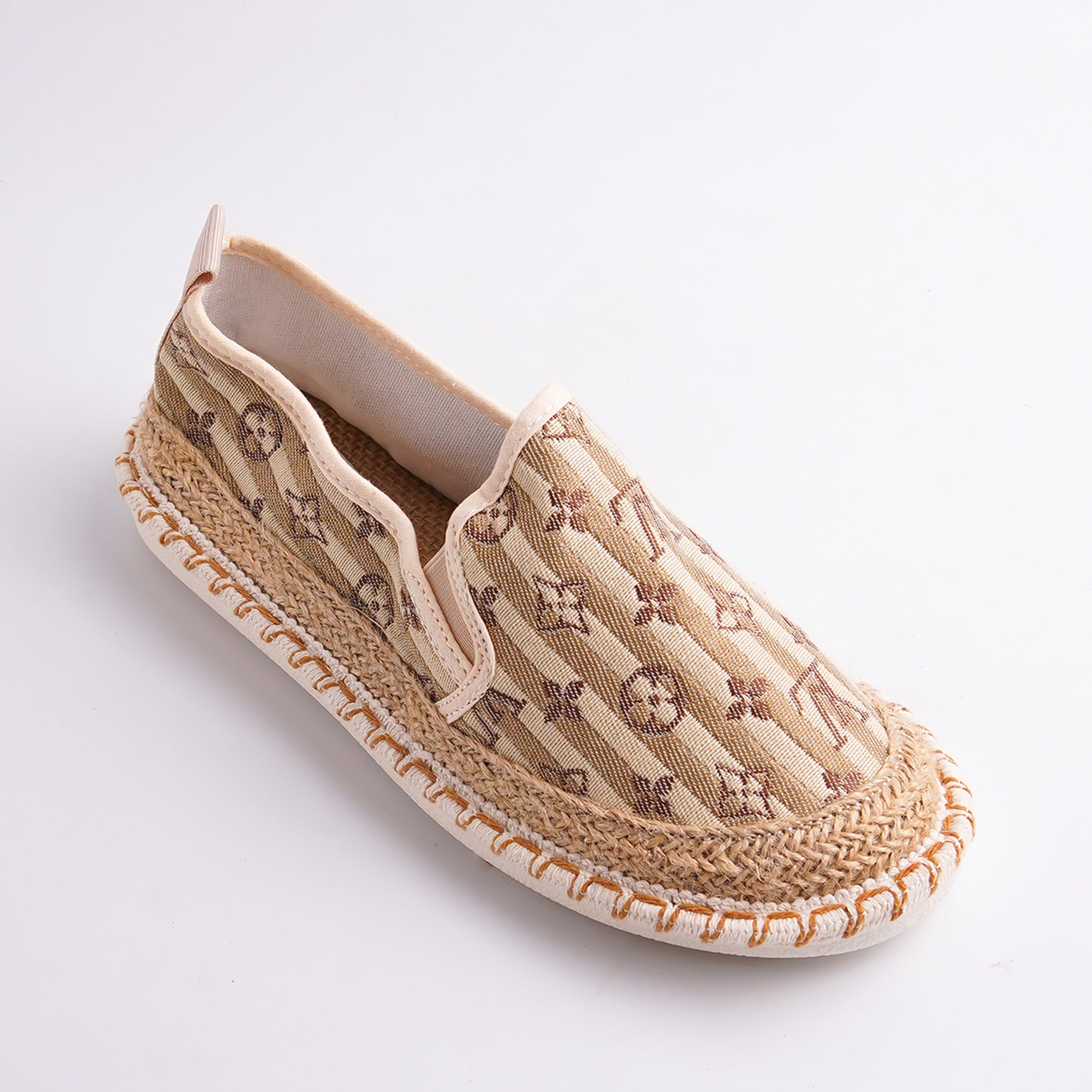 Beige espadrille shoe with woven details on a white background