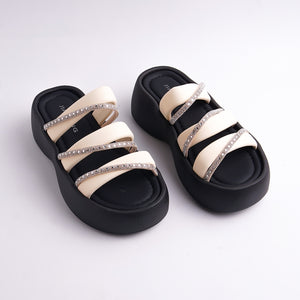Pair of black and beige sandals with rhinestone straps on a white background