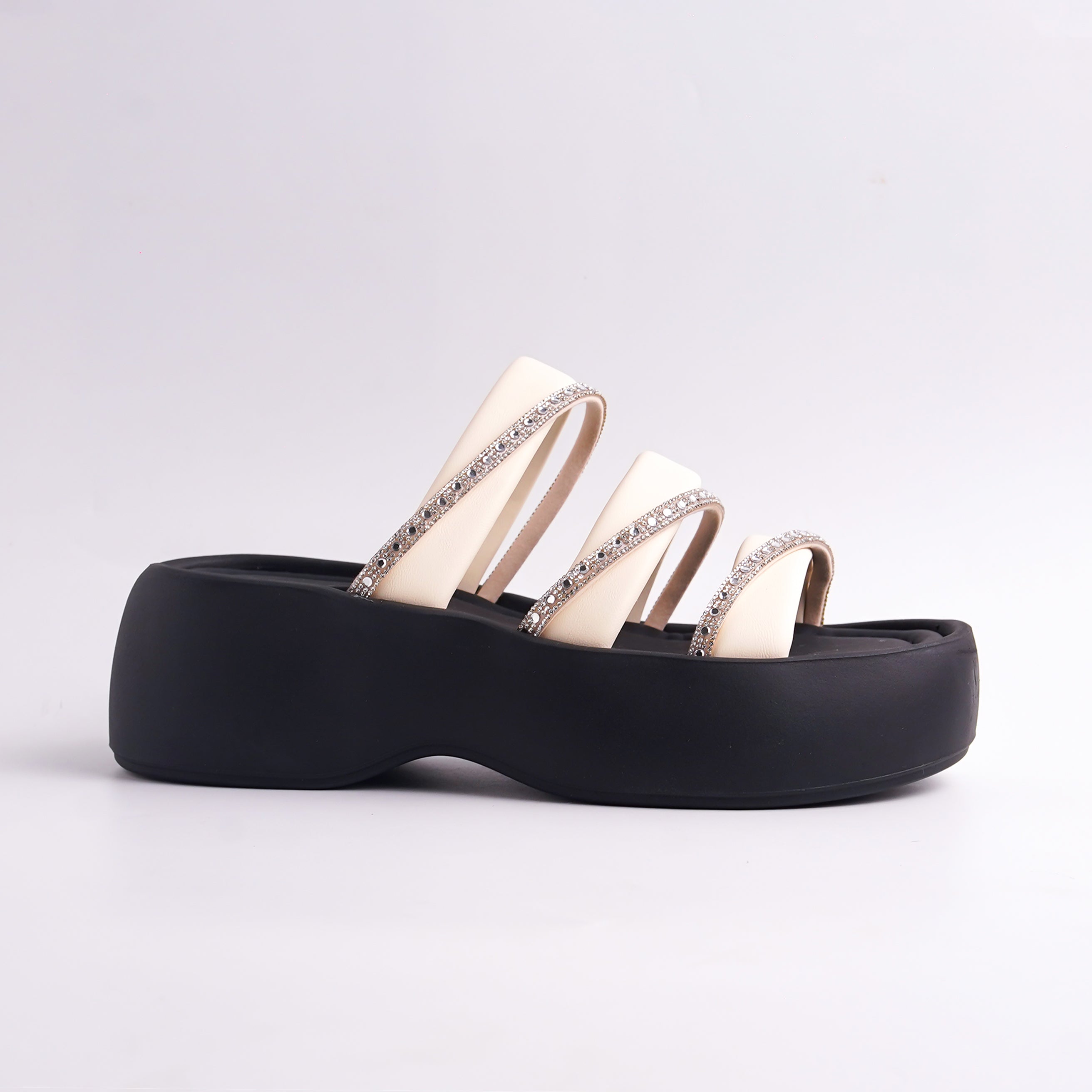 Black and beige sandals with decorative straps on a light gray background