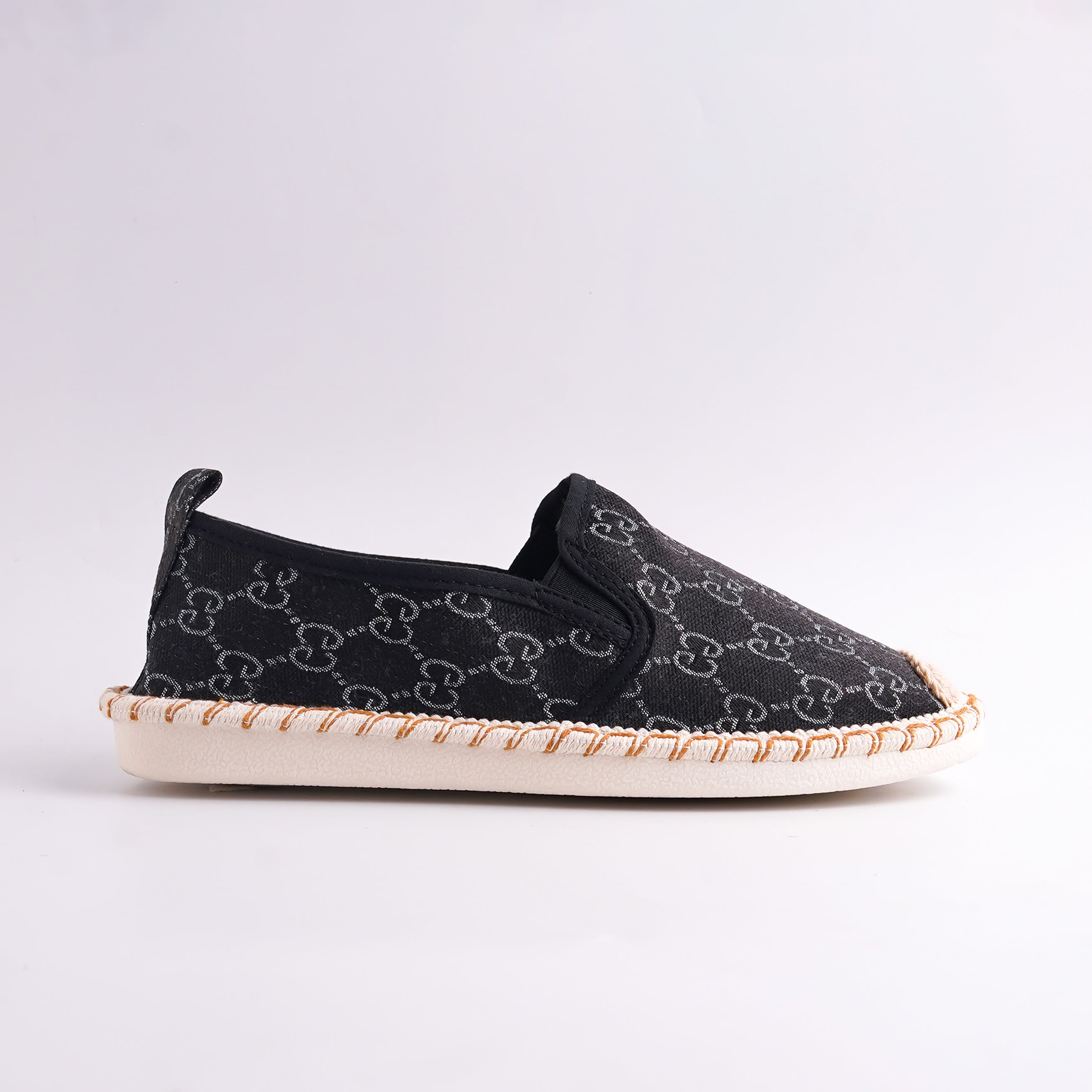 Black slip-on shoe with patterned sole on a light gray background