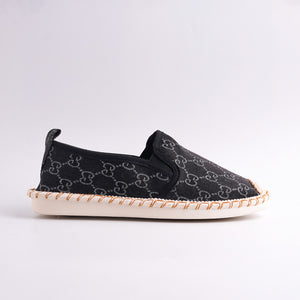 Black slip-on shoe with patterned sole on a light gray background