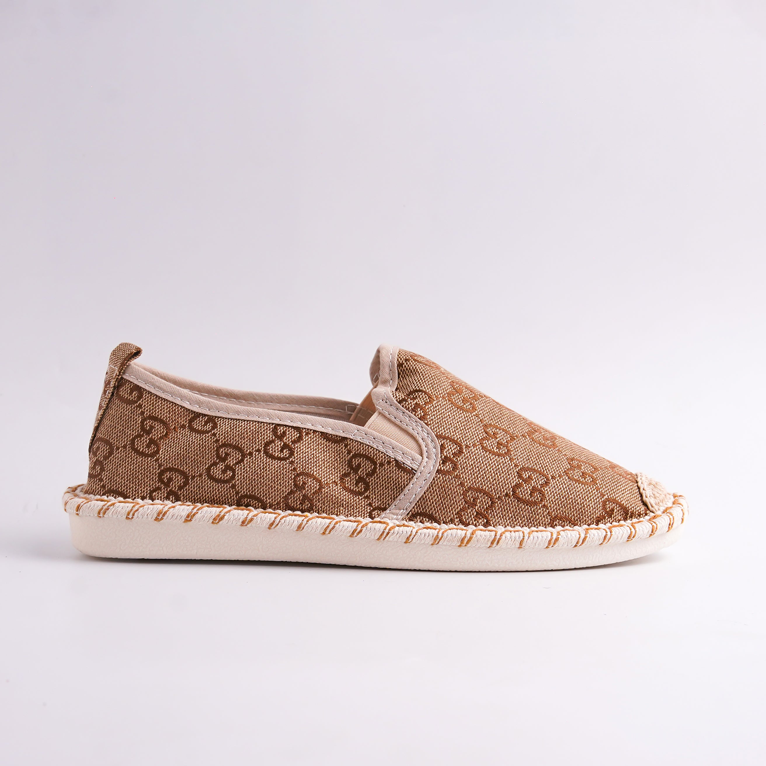 Beige slip-on shoe with patterned design on a light gray background