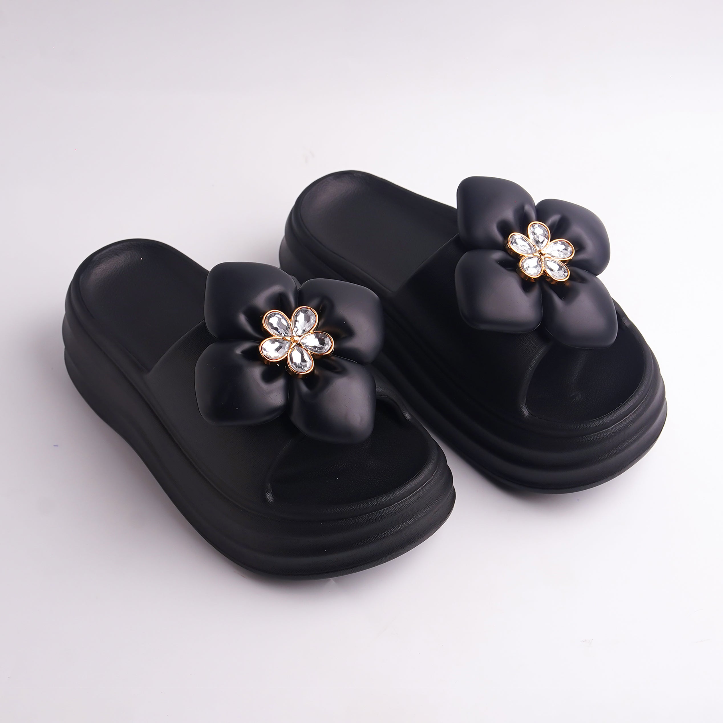 Pair of Black Platform Flower Slides with rhinestone jewel center on a white background.