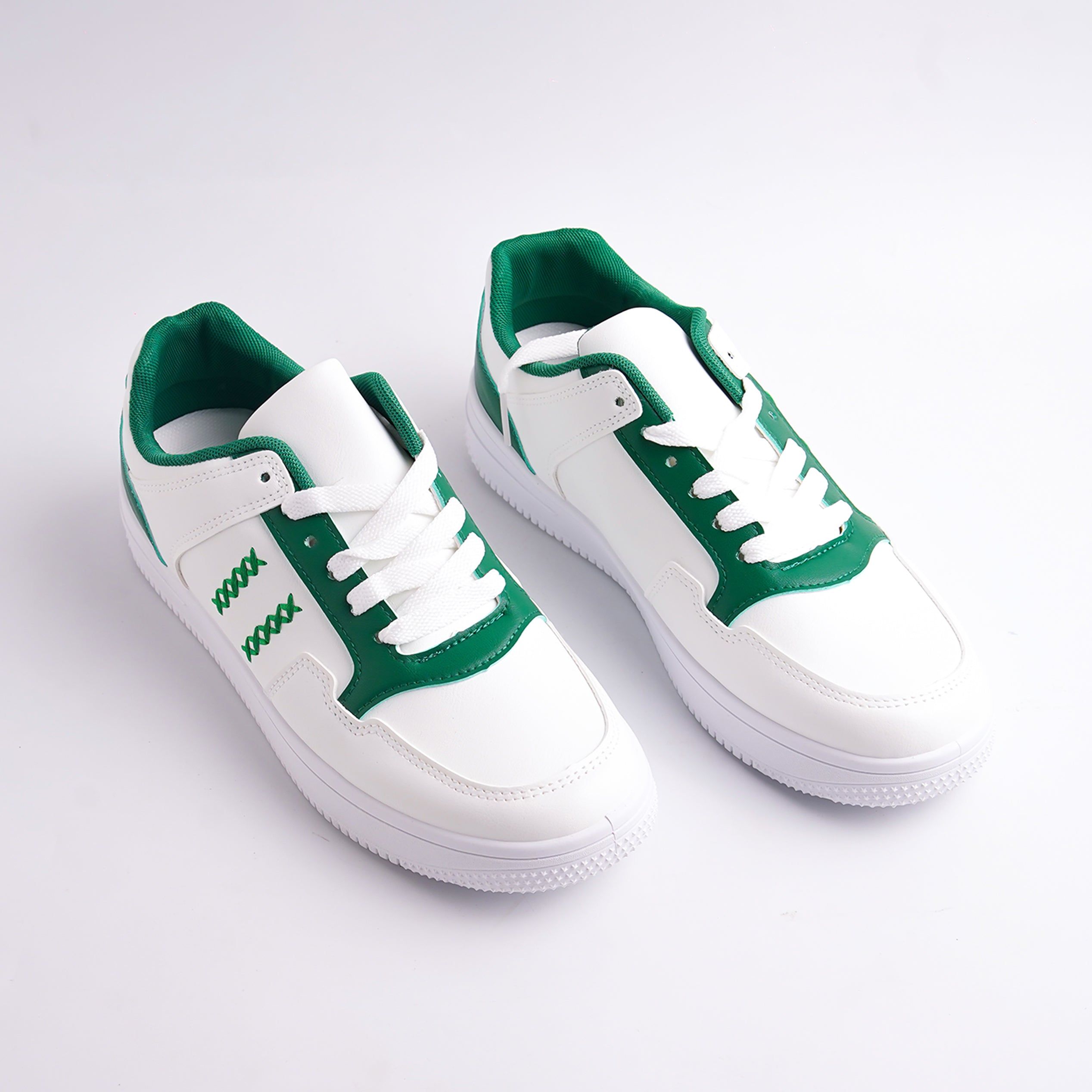 White sneakers with green accents on a light gray background