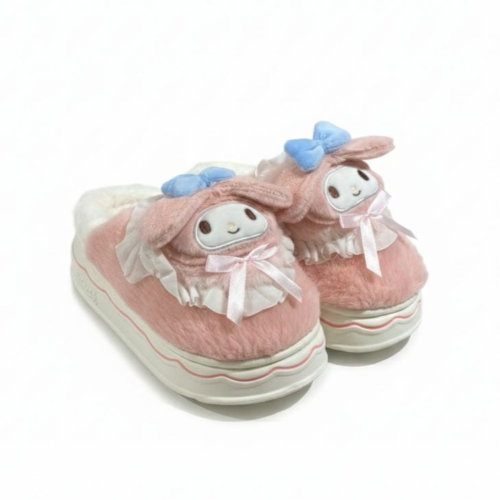 Pair of pink slippers with cartoon face design on a white background
